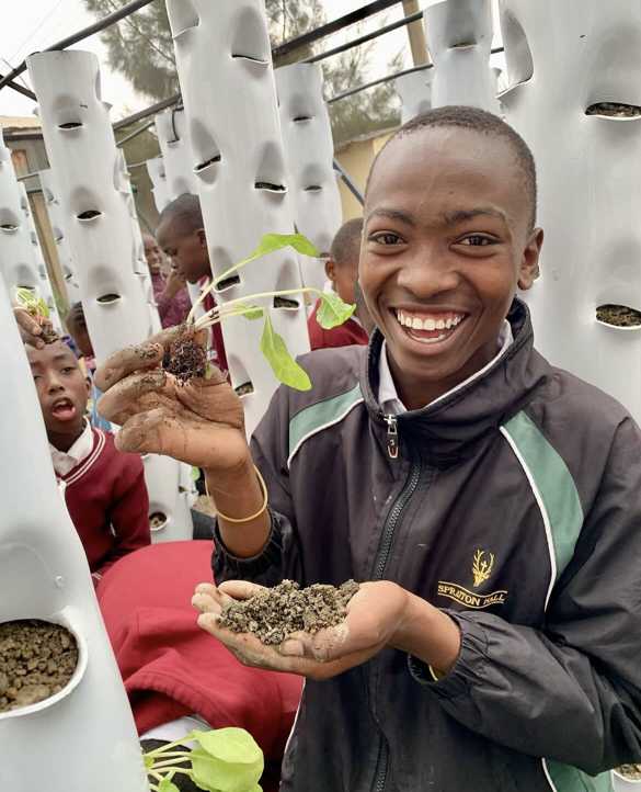 A girl smiling holding one of the plants from the greenhouse